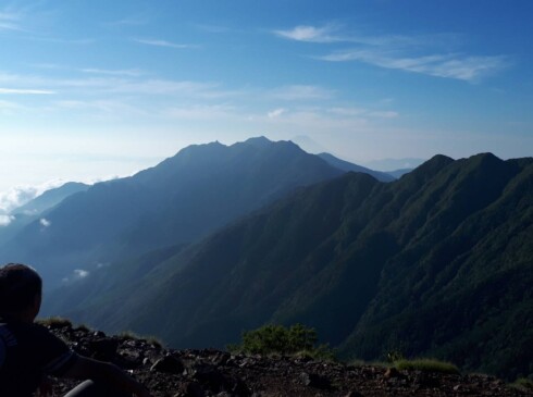 駒津峰から鳳凰三山、薬師岳の肩口にかすかに富士山を望む。朝日に輝く峰々が神々しい (T・O)