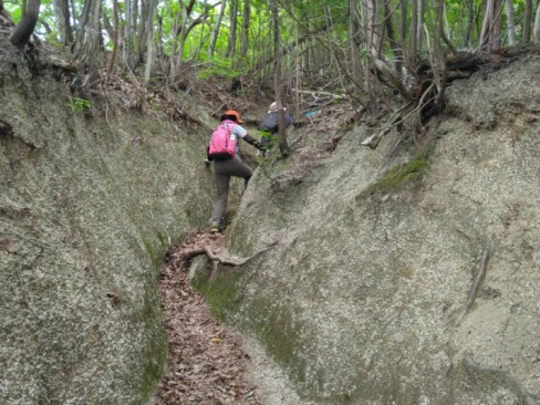 歩き始めてすぐに岩が雨水で深く浸食された間の登山道を進みます。